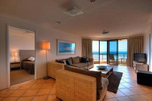 una sala de estar con sofá y una habitación con vistas. en San Simeon Beachfront Apartments Tugun, en Gold Coast