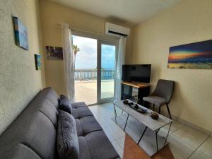 パフォスにあるPoseidon 51 - Beachfront Two Bedroom Apartmentのリビングルーム(ソファ、テーブル、テレビ付)