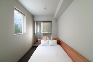 a bed in a room with a window at BUNSHODO HOTEL in Fukuoka