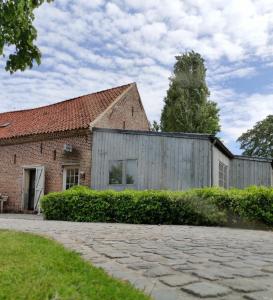 een oud bakstenen gebouw met een houten hek bij Het Ruytershuys in Tielt