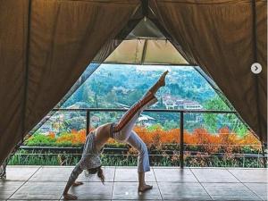 倫邦的住宿－特日茲拉度假酒店- 格拉姆營地，一位在窗前摆着瑜伽姿势的女人