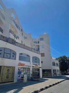 un gran edificio blanco con un cartel delante en Pearl City View Apartment, en Pafos