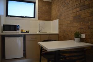 a kitchen with a table and a sink and a window at Beachfront Motel in Apollo Bay