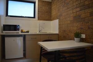 een keuken met een tafel, een wastafel en een raam bij Beachfront Motel in Apollo Bay