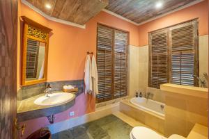 a bathroom with a sink and a tub and a toilet at Villa Angsa by Nakula in Sanur