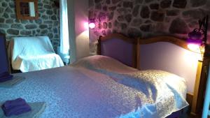 a bedroom with a bed and a stone wall at La myrtilleraie in Péreyres