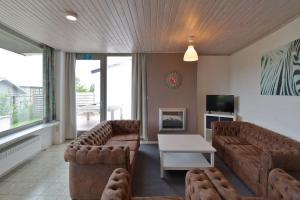 sala de estar con sofás, mesa y TV en Flanders Fields Cottage, en Beveren
