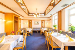 a restaurant with tables and chairs and a chandelier at Hotel Binzer Hof in Binz