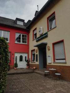 a red and white building with tables in front of it at Pension Breidbach in Ensch