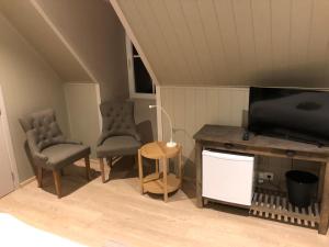 ein Wohnzimmer mit 2 Stühlen und einem Flachbild-TV in der Unterkunft B&B De Dulle Koe in Waregem