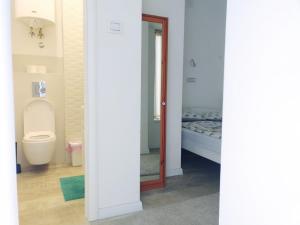 a bathroom with a toilet and a bed at Cricket Park Hostel in Belgrade