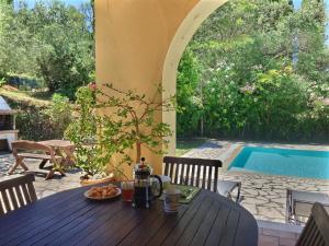a wooden table with a bowl of fruit on it next to a pool at Gastouri Villa Pascalia with heated pool in October and views in Achílleion