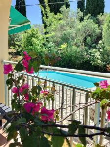 a balcony with pink flowers and a swimming pool at Gastouri Villa Pascalia with heated pool in October and views in Achílleion