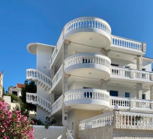 a white building with white balconies on it at Villa Maluma in Rogoznica