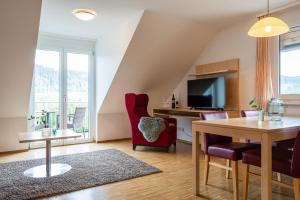 ein Wohnzimmer mit einem Tisch, Stühlen und einem TV in der Unterkunft NATURE TITISEE - Easy.Life.Hotel. in Titisee-Neustadt