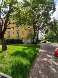 a yellow building with trees on the side of a street at Pastel Guest Rooms in Warsaw