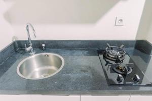 a kitchen counter with a sink and a stove at Lavish 2BR Apartment at Grand Sungkono Lagoon By Travelio in Surabaya +7 photos