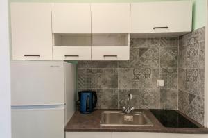 a kitchen with white cabinets and a sink at Alpha Studios in Arkasa