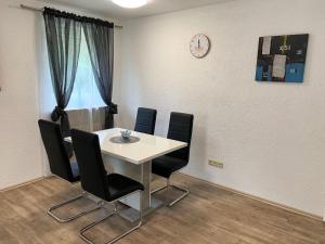 una mesa y sillas en una habitación con un reloj en la pared en Ferienwohnung Familie Schott, en Schwaig