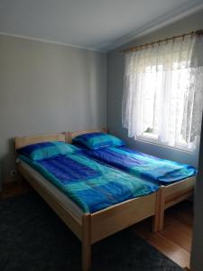Schlafzimmer mit einem Bett mit blauer Bettwäsche und einem Fenster in der Unterkunft MIWA - pokoje do wynajęcia in Mikołajki