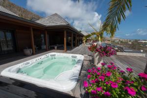 a hot tub on the deck of a house with flowers at Dream Villa Marigot 771 in Saint Barthelemy