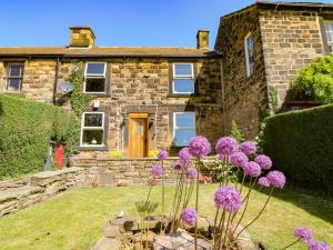 a stone house with purple flowers in the yard at 2 Snape Hill in Dronfield