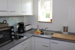 eine Küche mit einer Spüle und einer Mikrowelle in der Unterkunft Ferienwohnung Brüssing in Pentling