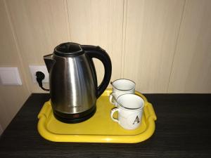 ノヴォロシースクにあるGuest House Yuzhnyyの茶ポット、黄色いトレイのカップ2杯