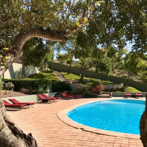 una piscina con tumbonas rojas y árboles en Finca El Otero, en Aigües