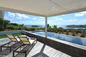 a patio with two chairs and a table and a swimming pool at Dream Villa Mont Jean 657 in Saint Barthelemy