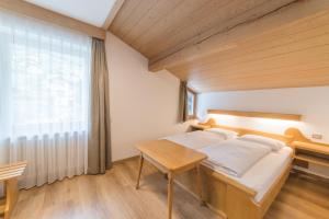 a bedroom with a bed and a table and a window at Pension Apartments Pardell in Kastelbell-Tschars