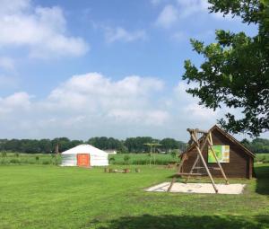 a playground with a slide and a barn at Iloons yurt in Hollandscheveld +18 photos