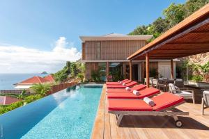 a row of red lounge chairs sitting next to a swimming pool at Dream Villa Corossol 706 in Saint Barthelemy
