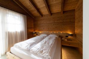 a bedroom with a white bed with a wooden wall at Chalet Schafberg in Wildhaus