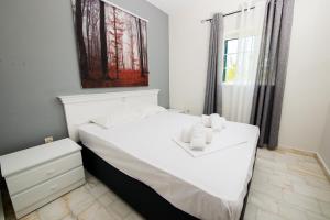 a white bed in a room with a window at Ifigenia's Apartments in Stoupa