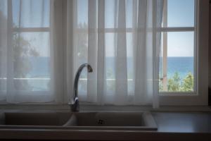 a kitchen sink in front of a window with the ocean at ammos seafront family apartments in Nea Plagia