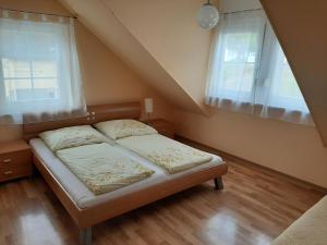 a bed in a room with two windows at Residenz Moselstausee in Sankt Aldegund
