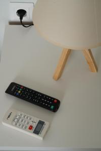 due telecomandi seduti su un tavolo accanto a una lampada di Smyrnis Apartments a Ermoupoli