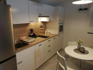 a kitchen with white cabinets and a table and a table and chairs at Apartmani Sandra i Davor Lonic in Kukljica
