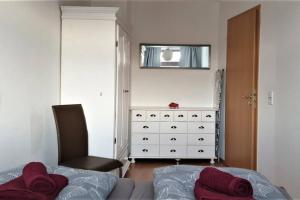 een slaapkamer met een bed, een stoel en een dressoir bij enjoy Leipzig FeWo Leipzig-Schönefeld in Leipzig