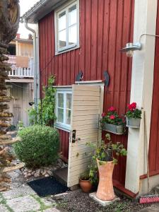 een rood huis met een houten deur en een aantal planten bij Pinglans bakficka in Gränna