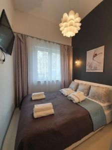 a bedroom with a large bed with two towels on it at DWIE SOSNY Apartamenty przy plaży - SAUNA, JACUZZI, SIŁOWNIA, BAWIALNIA - 365PAM in Ustronie Morskie