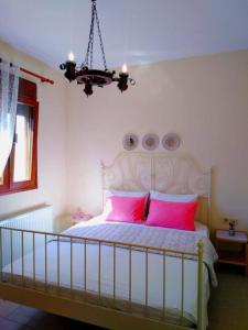 ネア・ムダニアにあるVilla Annaのベッドルーム1室(ピンクの枕とシャンデリア付きのベッド1台付)