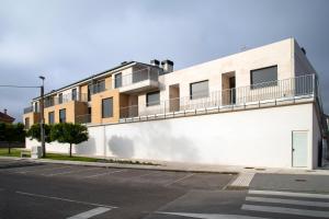 a white building with a balcony on the side of it at Apartamentos Salitre in Soto de la Marina