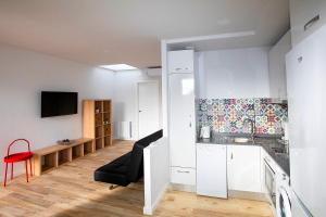 a kitchen with white cabinets and a red chair in a room at Apartamentos Salitre in Soto de la Marina