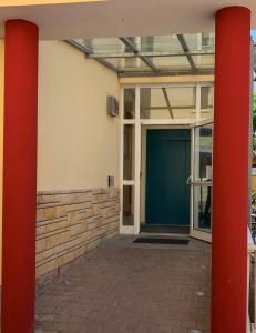 uma porta da frente de um edifício com duas colunas vermelhas em The KRAL - Business Hotel & Serviced Apartments em Erlangen