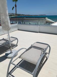 a chair on a balcony with the ocean in the background at Karousos Beach Rooms in Ayia Napa