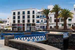a large white building with palm trees in front of it at Living El Charco, piso individual in Arrecife