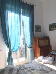 パレルモにあるGò Gò House 2 Casa Aprileのベッドルーム1室(ベッド1台、青いカーテン付きの窓付)