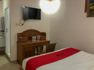 um quarto com uma cama, uma secretária e uma televisão em RedDoorz near XT Square 3 em Yogyakarta